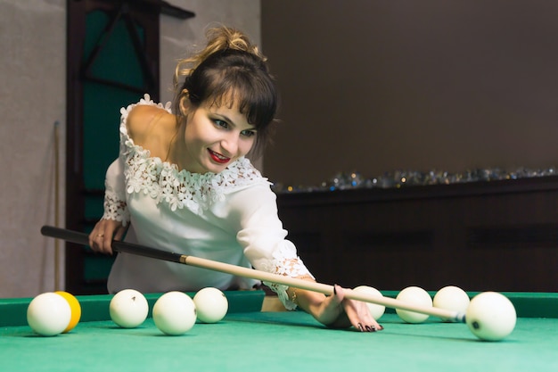 Brunette woman plays billiards