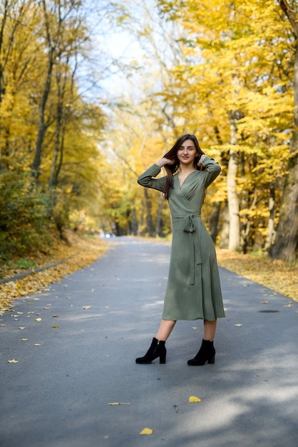 Brunette woman portrait in autumn park wearing olive dress