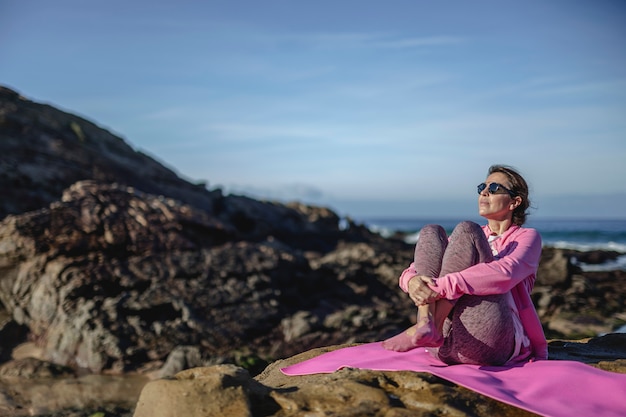 Brunette woman practicing yoga on the beach