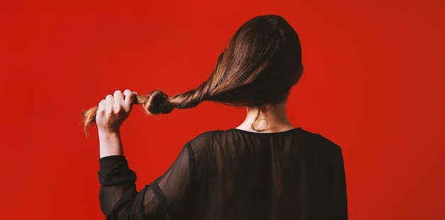 Photo brunette woman pulling her long hair with knot it