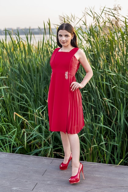 Brunette woman in a red dress on the seashore