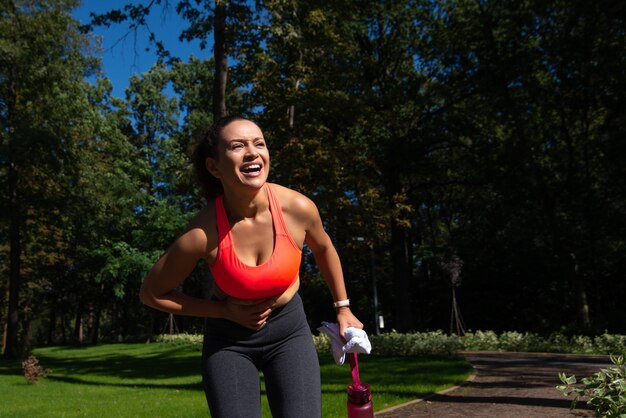 Brunette woman runner having stomach cramps after running outdoor. Sport injury