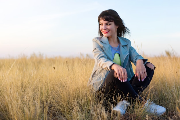 Brunette woman sitting in yellow steppe grass