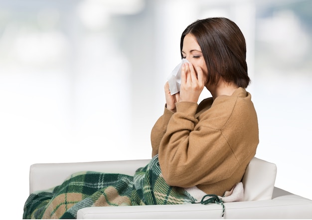 Brunette woman sneezing in a tissue in the living room