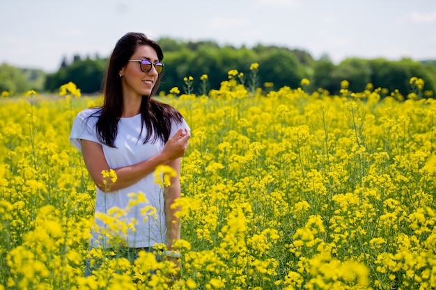 Brunette woman in sunglasses in the middle of blooming field