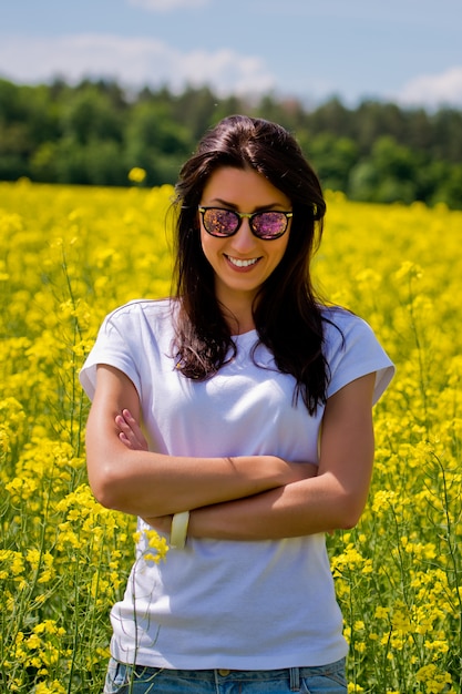 Brunette woman in sunglasses in the middle of blooming field