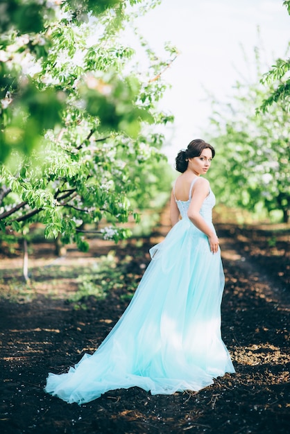 Brunette woman in a turquoise dress walking in the spring garden