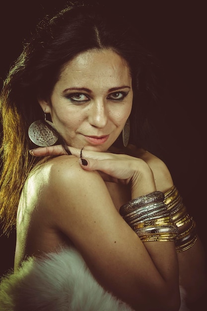 brunette woman wearing white fur and gold jewelry