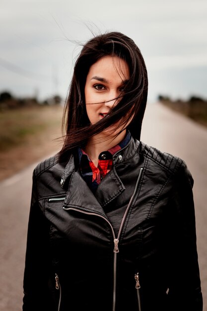 Brunette woman with black leather jacket in a road 