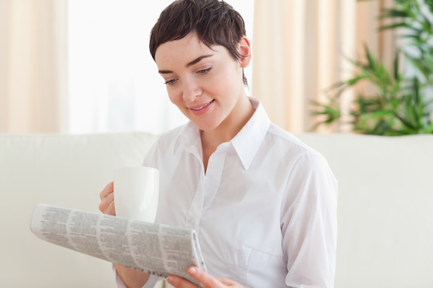 Brunette woman with a cup and a newspaper