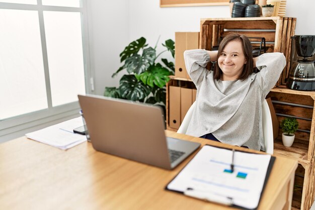 Brunette woman with down syndrome stretching arms relaxing at business office