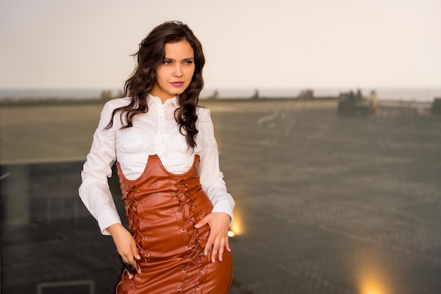 Brunette woman with a fashionable pose in the city next to a mirror