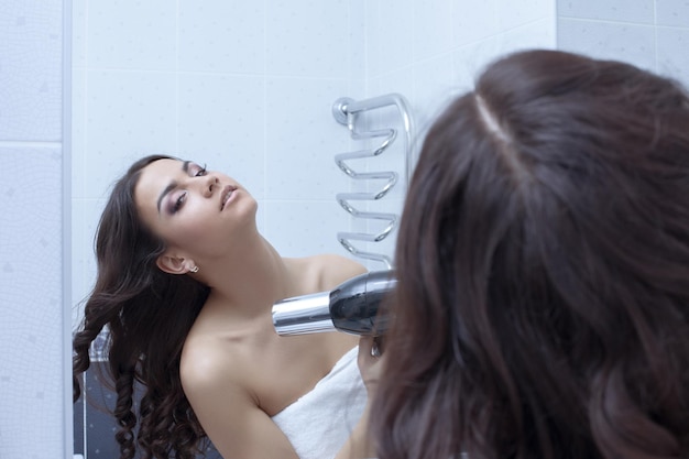 Brunette woman with hairdryer in bathroom