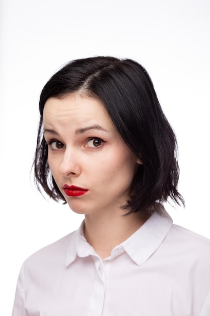 brunette woman with red lipstick on her lips in white shirt white background High quality photo