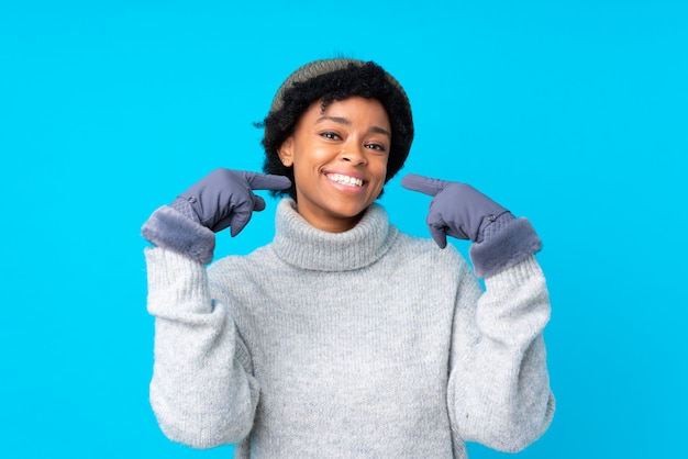 Brunette woman with winter hat over isolated blue background