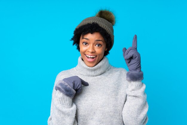 brunette woman with winter hat over isolated blue background