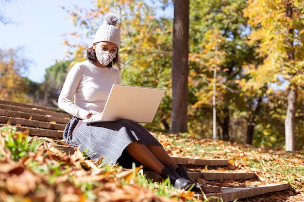 Brunette woman working with her laptop outdoors.