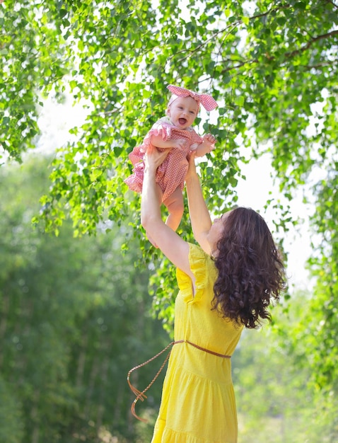 Una donna bruna, una giovane madre con una bambina che passeggia nel parco