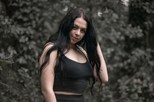 A brunette young girl in a black dress alone in the forest