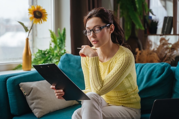 Brunette young woman fills in the information in the questionnaire making an application for hire on