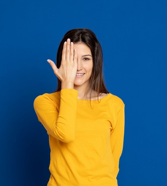 Giovane donna castana che gesturing sopra la parete blu