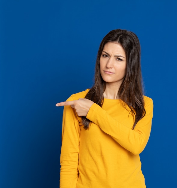 Brunette young woman gesturing over blue wall