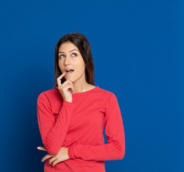 Brunette young woman gesturing over blue wall