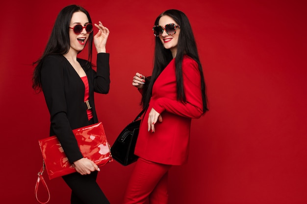 Brunettes in suits and glasses standing back to back