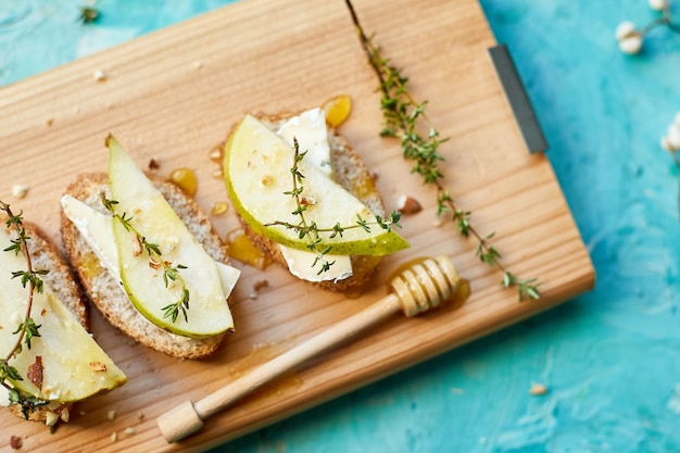 Bruschetta antipasto with blue cheese and pear on wooden board