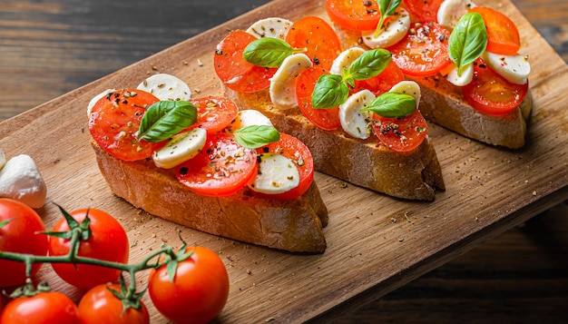 Foto bruschetta caprese foglie di basilico fresco pomodori aromatici maturi e mozzarella italiana su bruschetta condita con olio d'oliva e cosparsa di pepe ed erbe aromatiche