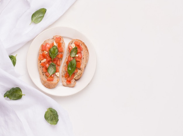 Bruschetta is een traditioneel Italiaans gerecht met tomaat, knoflook op een bord naast een doek en basilicumblaadjes. kopieer ruimte