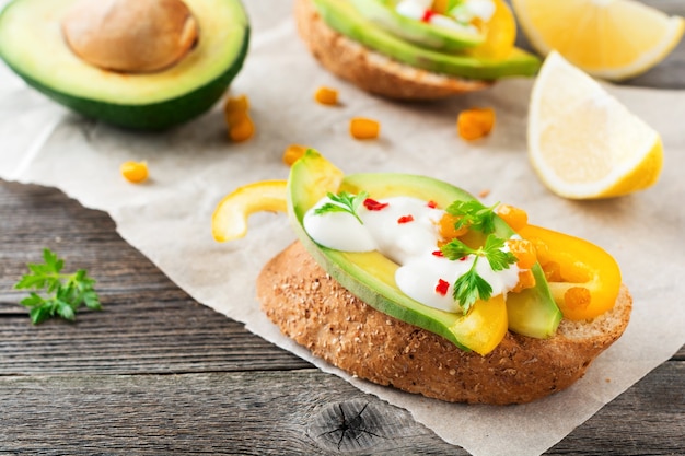 Bruschetta met avocado, gele peper, maïskorrels, peterselie en chilipepers