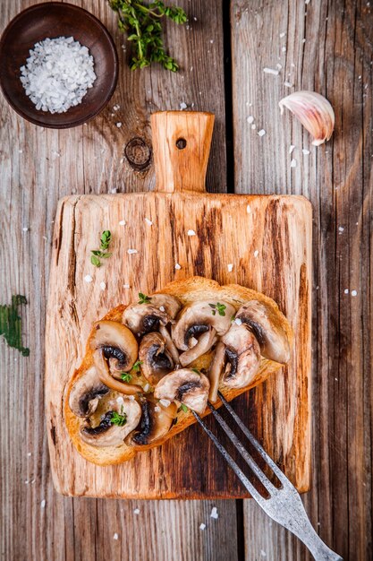 Bruschetta met gebakken champignons op houten snijplank