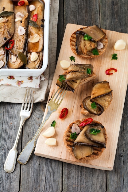 Bruschetta met gemarineerde aubergine met chili, knoflook en peterselie op een houten voet