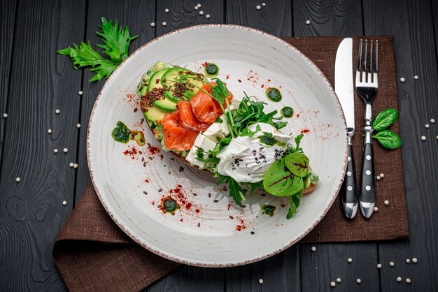 Bruschetta met gesneden avocado feta kaas pestosaus gepocheerd ei en gezouten zalm