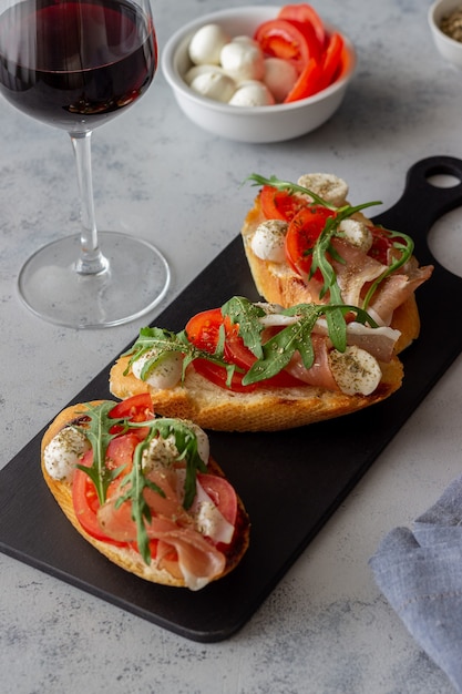 Foto bruschetta met ham, mozzarella, tomaten en rucola. wijn voorgerecht. snack.