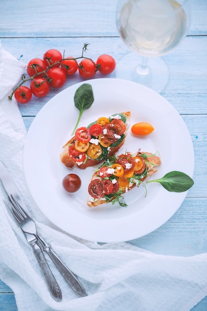 Bruschetta met kaas, basilicum, rucola en cherrytomaatjes en een glaasje witte wijn