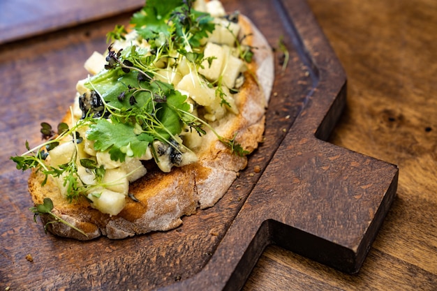 Bruschetta met kaas en groenten op een houten snijplank voor foto's en video-opnamen.