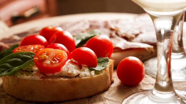 Bruschetta met kerstomaatjes. Wijnglas, Italiaans voorgerecht. Ambachtelijke papier achtergrond. Picknick concept