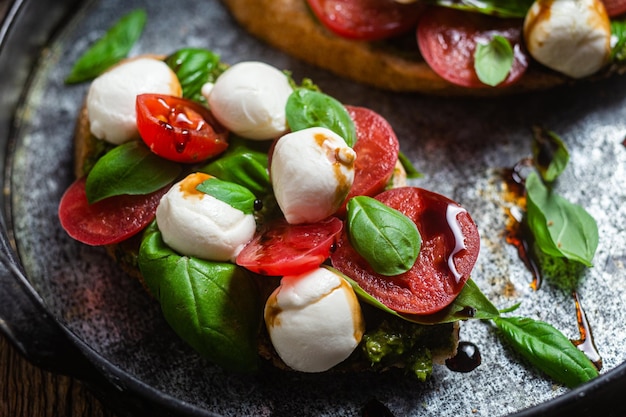 Bruschetta met mozzarella tomaten basilicum en pesto op een bord Bruschetta Caprese