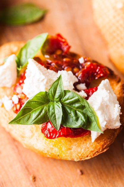 Bruschetta met olijfolie, zongedroogde tomaten, feta en verse basilicum