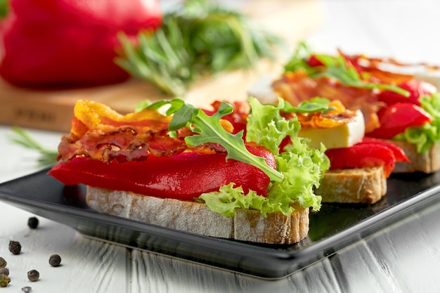 Bruschetta met paprika en spek fetakaas in een zwarte plaat op een witte achtergrond