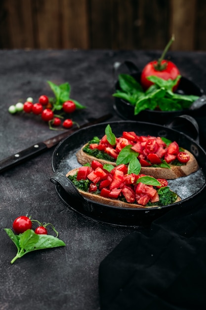 Bruschetta met pesto en tomaten op een donkere achtergrond