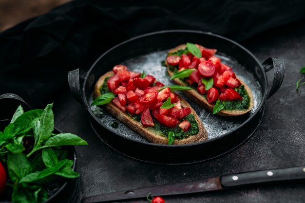 Bruschetta met pesto en tomaten op een donkere achtergrond