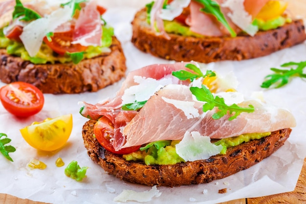 Bruschetta met prosciutto avocado tomaatjes rucola en Parmezaanse kaas