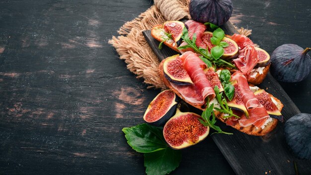 Bruschetta met prosciutto verse vijgen en kaas op de oude achtergrond gezonde voeding vrije ruimte voor tekst bovenaanzicht