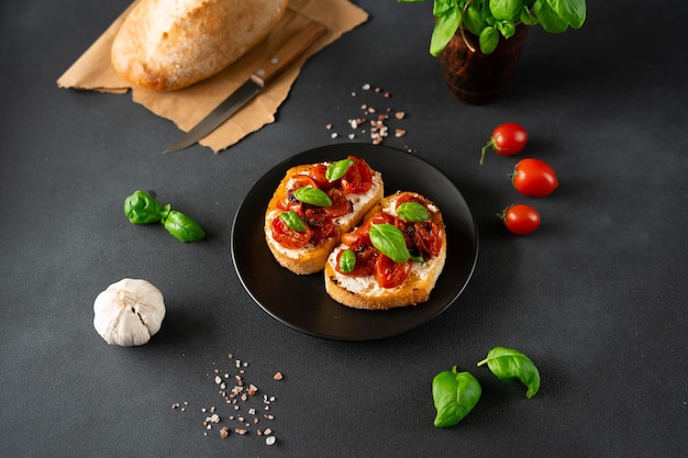 Bruschetta met ricotto kaas en cherrytomaatjes basilicum knoflook op een zwarte achtergrond