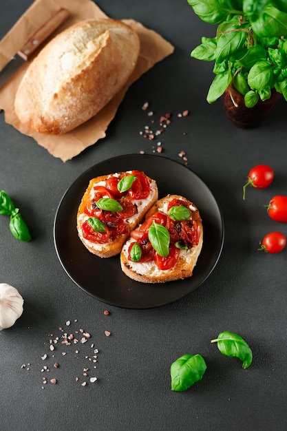 Bruschetta met ricotto kaas en kerstomaatjes basilicum knoflook op een zwarte achtergrond bovenaanzicht