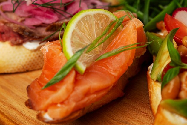 Bruschetta met rode gezouten vis en citroen op een houten bord. Smakelijk tussendoortje en voorgerecht. Selectieve aandacht. Gezonde voeding eten. Detailopname.