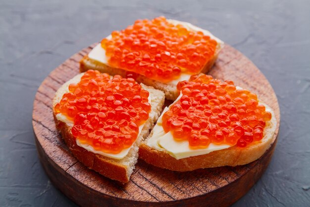 Bruschetta met rode kaviaar op een houten bord op een grijze achtergrond. Horizontale foto